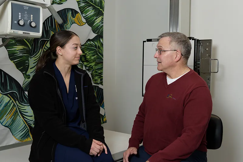 Healthcare professional consulting with a male patient in a medical office setting.