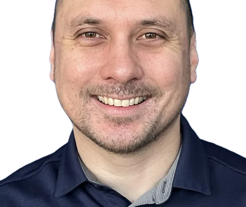 Man smiling in a navy blue shirt against a plain background.