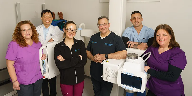 Medical team posing with radiology equipment in a healthcare facility.